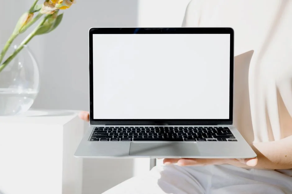 Woman in floral dress shopping online with a laptop and credit card indoors.